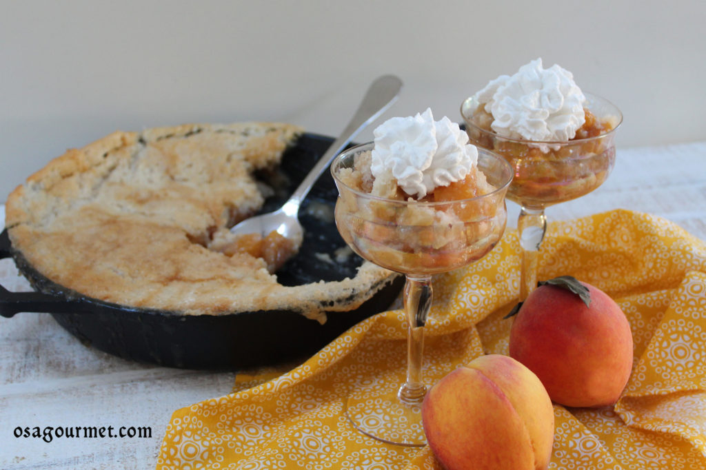 Peach cobbler in a skillet with 2 dishes of pech cobbler in front