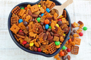 trail mix in a blue bowl with wooden scoop
